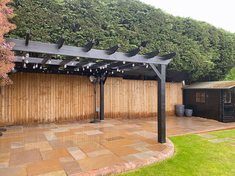 Paved garden seating area with pergola and timber fencing
